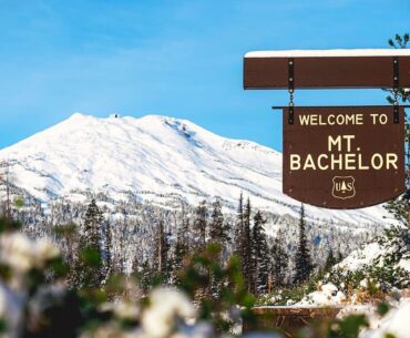 The Mt. Bachelor sign and ski resort in the background on a sunny day.