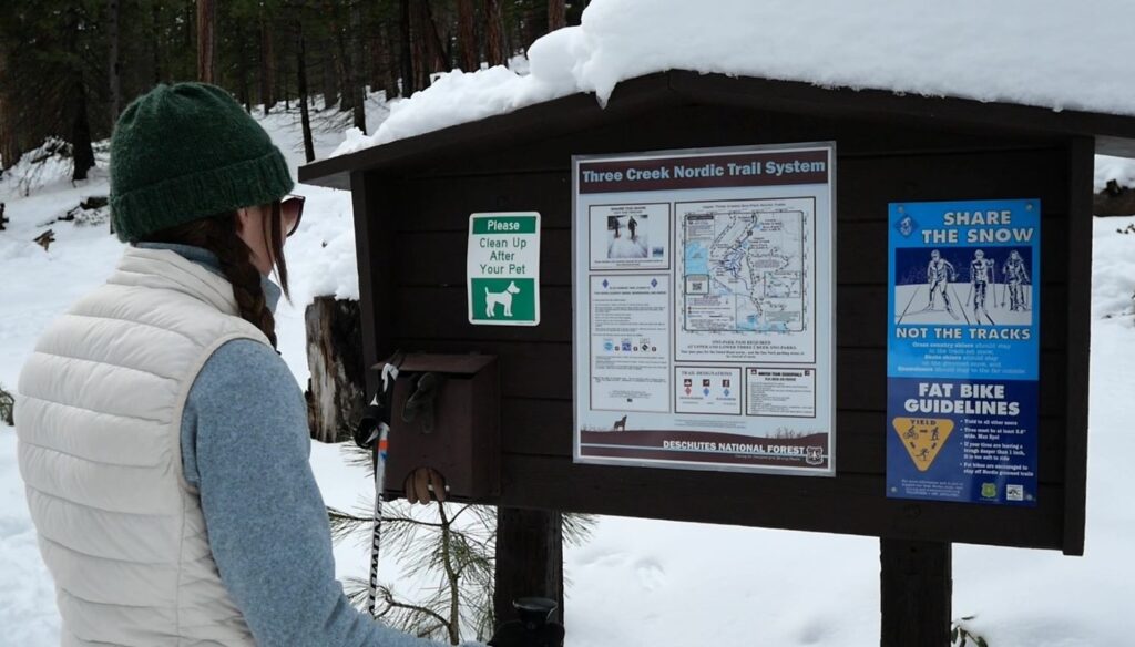 Abby looking at the trail map at the entrance of Three Creek Sno Park.