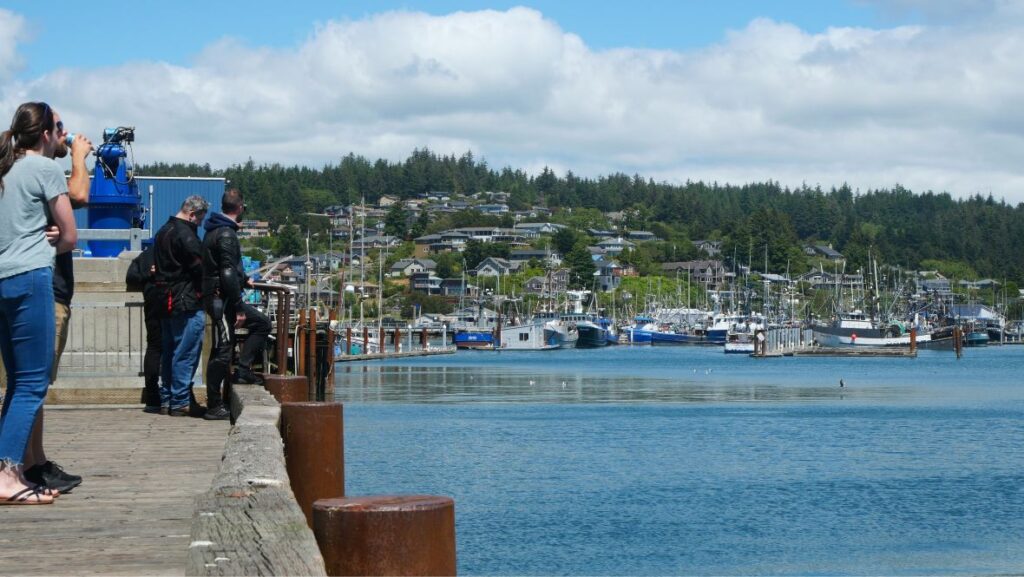 Visitors taking in views of the marina in Yaquina Bay in Newport Oregon on a sunny day.