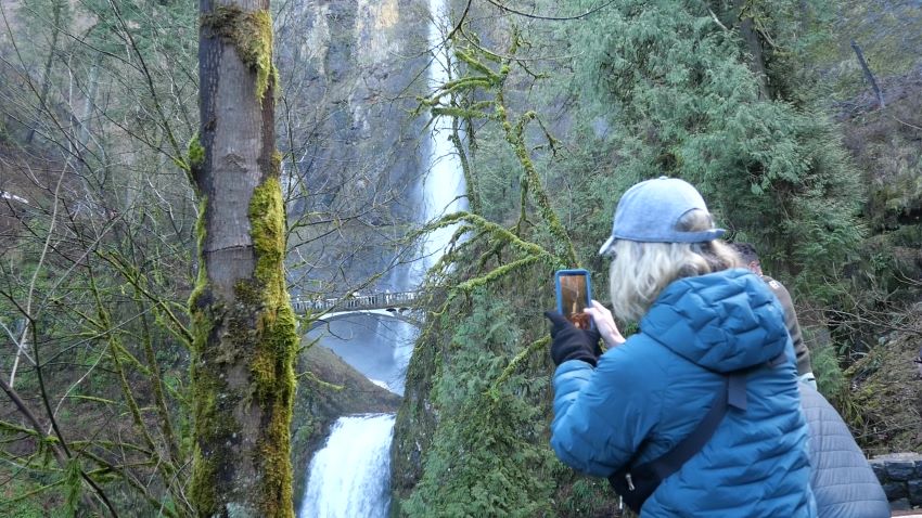 A visitor taking a photo of Multomah Falls