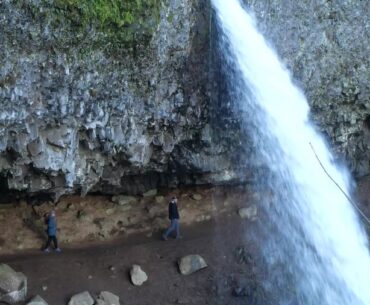 Visitors walking behind Ponytail Falls