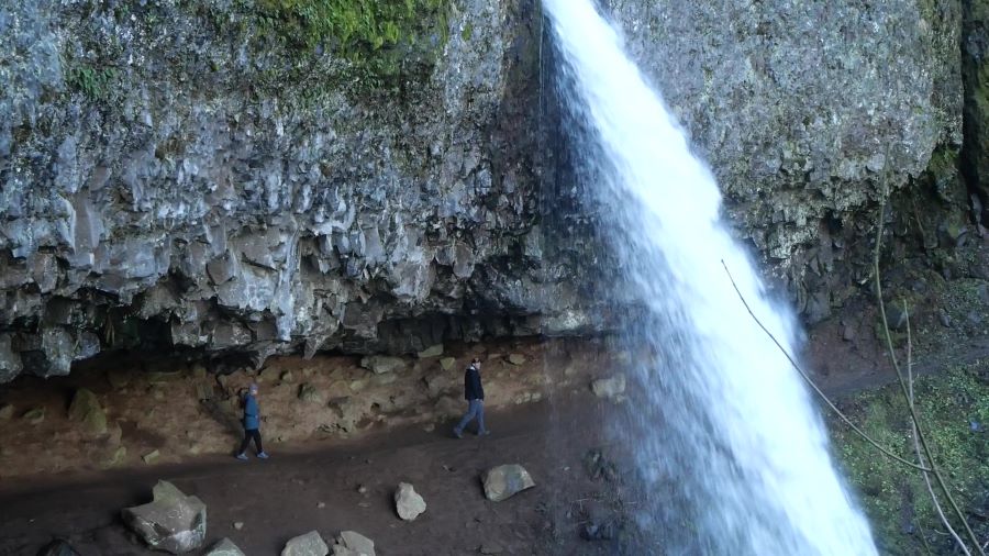 Visitors walking behind Ponytail Falls