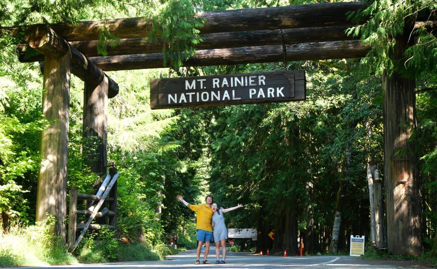 Us posing under signage at one of the entrances to Mt. Rainier National Park.