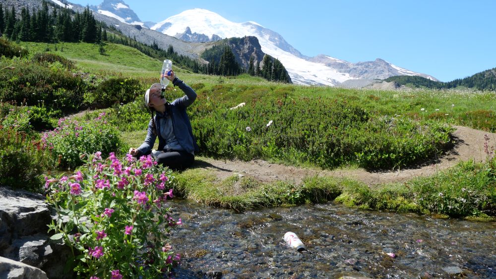 Abby filtering and drinking water from a stream on the Wonderland Trail. 