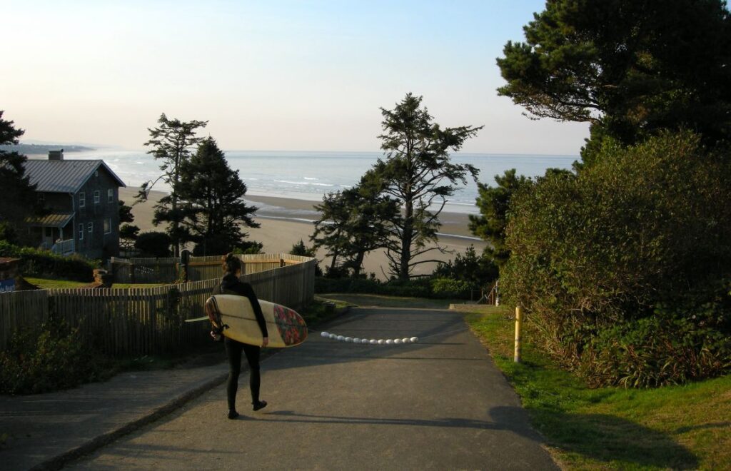 A surfer heading down to Agate Beach to surf.