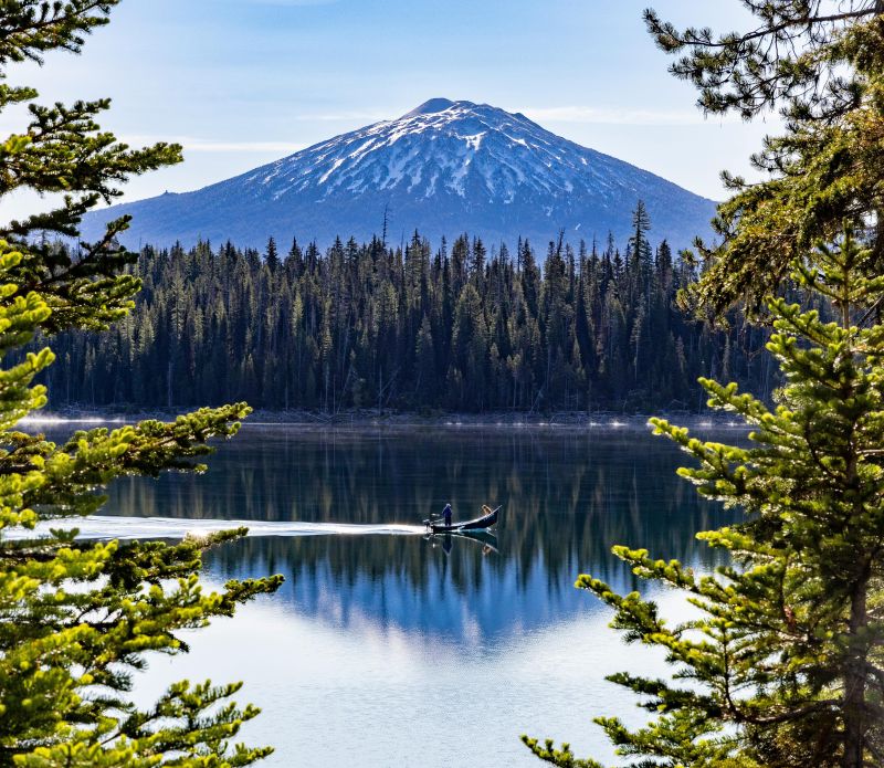 A boat gliding across Elk Lake Oregon with Mt. Bachelor in the background.