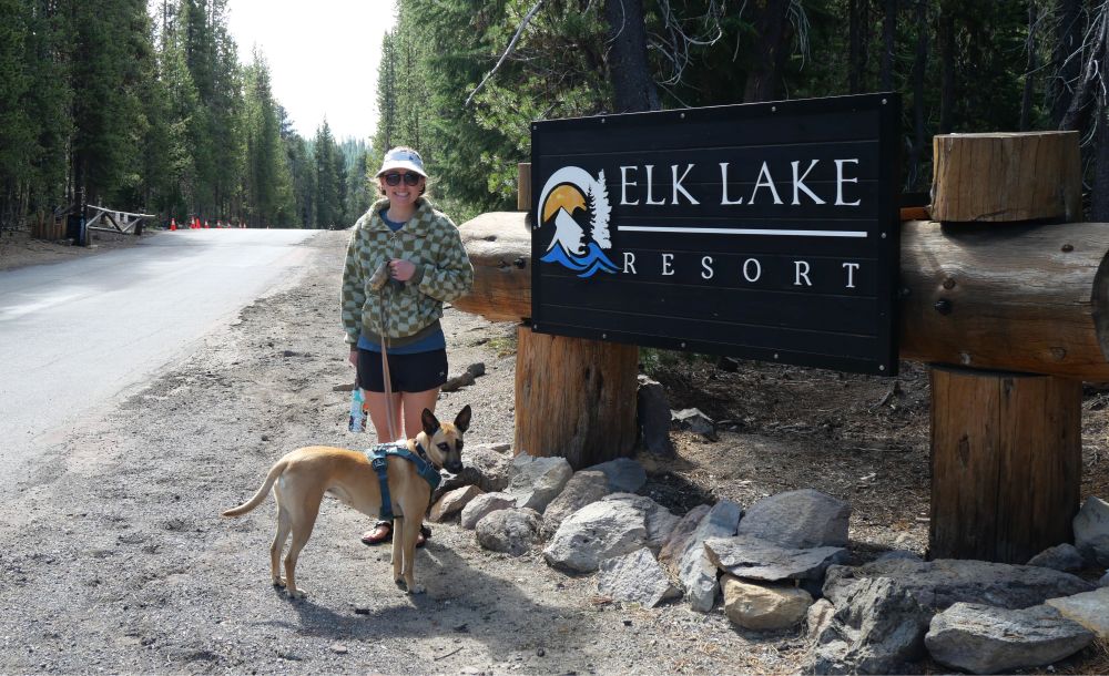 Abby in front of a sign at Elk Lake Resort.